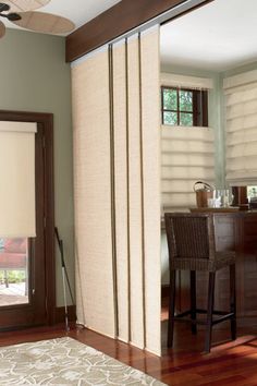 a living room filled with furniture and a large window covered in blind shades next to a bar