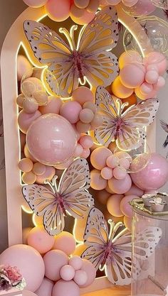 a display with balloons, butterflies and other decorations on it's side wall in a room