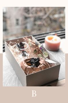 an open box sitting on top of a window sill next to a cup and saucer