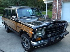 a black and brown jeep parked in front of a house