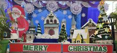 a christmas display in front of a building with santa clause on the roof and other decorations