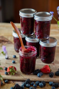 blueberries and raspberry jam in mason jars with a wooden spoon