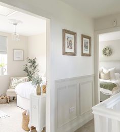 a bedroom with white furniture and pictures on the wall