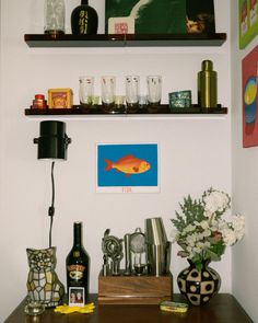 the shelves above the desk are filled with bottles and vases, cups, and other items