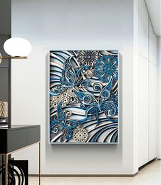 a blue and white painting hanging on the wall next to a table with a lamp