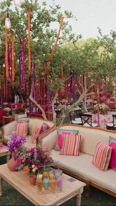 an outdoor seating area with couches, tables and flowers in vases on the table