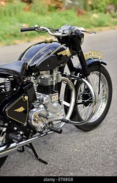 a black motorcycle is parked on the side of the road with grass in the background