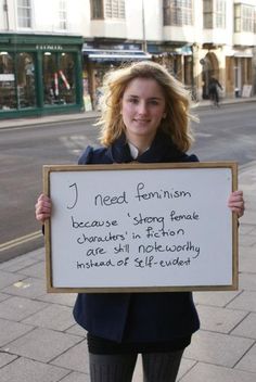 a woman standing on the sidewalk holding a sign