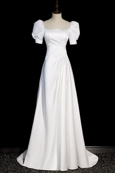 a white wedding dress on display in front of a black background