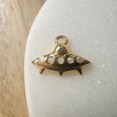 Whether you're a 👽 believer or not, this mini mothership charm is too cute to pass up. Wear it on it's own or on a jumble alongside your favorite charms on a necklace, bracelet, or strung upon hoops. Charm measures 6mm x 12mm. Simulated opal. Comes with a removable oval jump ring. Our materials make for an amazing, high quality, seamless, jewelry piece with longevity. Our rings are plated with 18k gold, 18k rose gold, or sterling silver and finished with a protective coating. A little secret we Dainty Nickel-free Round Pendant Charms, Dainty Nickel-free Dangle Charm Necklaces, Spiritual Dangle Charms For Gifts, Spiritual Dangling Charms For Gifts, Novelty Gold Jewelry Gift, Dainty Charms Suitable For Gifts, Dainty Tiny Charms For Gifts, Tiny Dainty Charms As Gifts, Dainty Handmade Pendant Charms