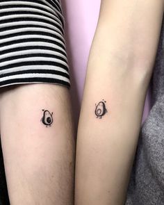 two people with matching tattoos on their arms, one is holding the other's arm