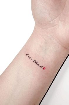 a small tattoo on the wrist that reads, love is forever with a red heart