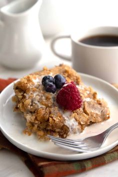 a white plate topped with fruit and granola next to a cup of coffee on a table