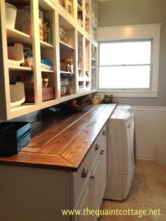 a kitchen with white cabinets and wooden counter tops in front of a window on the far wall