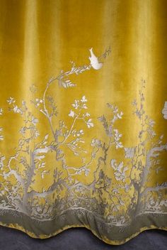 a yellow curtain with white flowers and birds on it