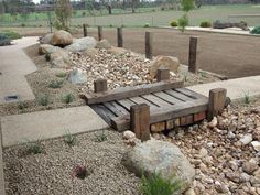 a wooden bench sitting on top of a pile of rocks next to a gravel field