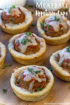 mini pizzas with meat and cheese in them on a wooden board, ready to be eaten