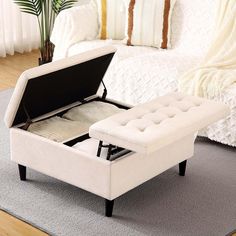 a white ottoman sitting on top of a carpeted floor next to a large bed