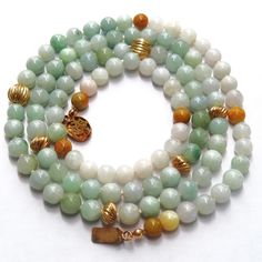 On offer is this beautiful Vintage Chinese Translucent Green White and Russet Jadeite Jade Necklace featuring genuine untreated jadeite gems and gold filled corrugated spacer beads with a Chinese gold filled box clasp with a Chinese character. Hand knotted with silk cord and a versatile opera length of 33 inches. The gold filled clasp has the initials SG on the back and closes tightly. Very highly polished large 8mm green and white jadeite gems gleam against your skin when worn. There are imperi Spiritual Gold Jade Beaded Necklaces, Spiritual Gold Jade Beaded Necklace, Single Strand Jade Beaded Necklace For Healing, Spiritual Single Strand Jade Beaded Necklace, Green Amazonite Jewelry With 8mm Beads, Chinese Gold, Jade Bead Necklace, Green Veins, Chinese Jade