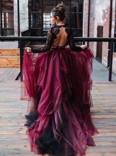 a woman in a long purple dress is sitting on a balcony with her back to the camera