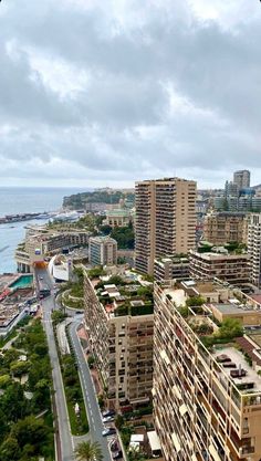 an aerial view of a city with tall buildings next to the ocean and trees on both sides