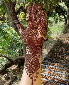 a hand with henna on it and trees in the background