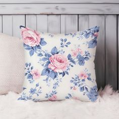 a white pillow with pink and blue flowers sitting on top of a fur covered bed