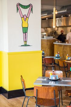 the interior of a restaurant with tables, chairs and artwork on the wall behind them