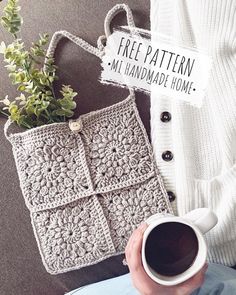 a woman holding a cup of coffee next to a crocheted bag and plant