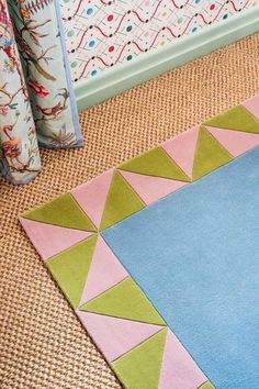 a blue rug with pink, green and yellow triangles on the floor in front of a wall