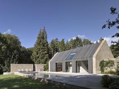 a house with a pool in the middle of some grass and trees around it on a sunny day