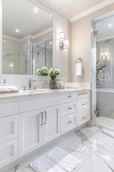 a large bathroom with white cabinets and marble flooring is pictured in this image, there are flowers on the counter