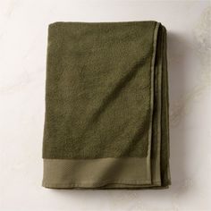 the folded green towel is on top of a white table