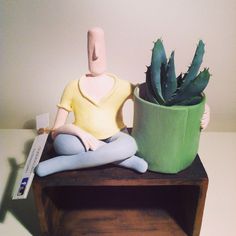 a clay figurine sitting on a table next to a potted plant