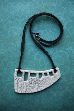 a white and black necklace is on a blue background with an intricate design in the middle