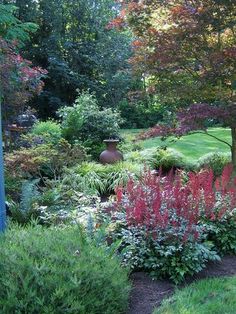 a garden filled with lots of different types of flowers and plants next to a tree