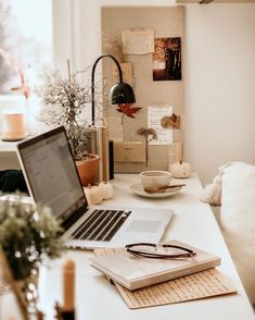 an open laptop computer sitting on top of a white desk next to a cup and saucer