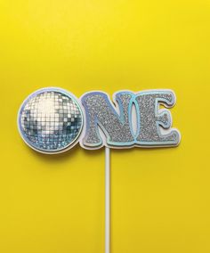 a cake topper that says one on it with a disco ball in the middle