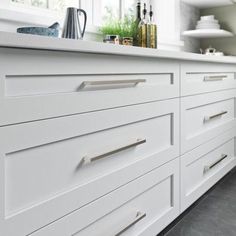 a kitchen with white cabinets and counter tops