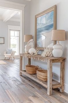 a wooden table topped with baskets under a painting next to a lamp and two lamps