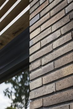 the corner of a brick building with a window in the back ground and trees in the background