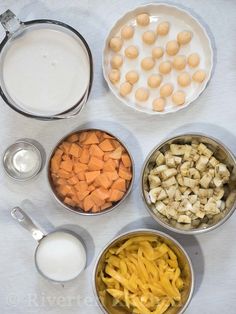 four bowls filled with different types of food on top of a white table cloth next to measuring cups and spoons