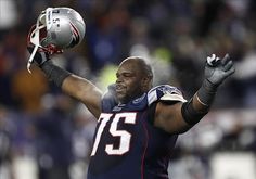 a football player with his arms in the air and holding a helmet on his head