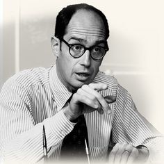 a black and white photo of a man with glasses looking at something in his hand