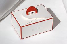 an open white box with a red and black object in the top corner on a white surface