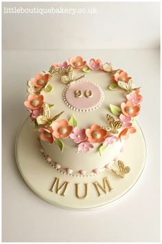 there is a cake with flowers on it and the name mum written in gold letters