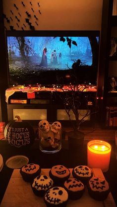 halloween cupcakes on a table in front of a flat screen tv with candles