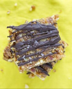 two pieces of food with chocolate drizzled on them sitting on a yellow surface