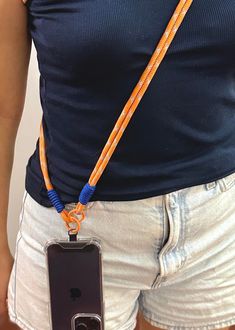 a woman wearing an orange and blue lanyard with her cell phone attached to it