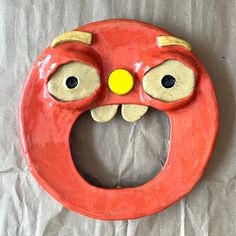 a ceramic red object with eyes and nose